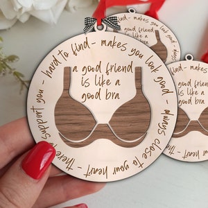 May include: A wooden ornament shaped like a bra with the text "Hard to find - makes you look good - Always close to your heart - There to support you - A good friend is like a good bra" engraved on it.
