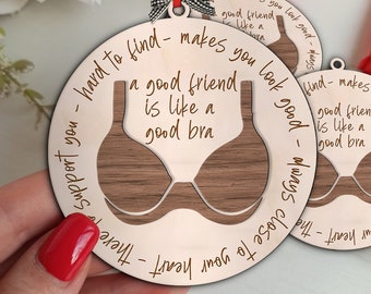 May include: A wooden ornament shaped like a bra with the text "Hard to find - makes you look good - Always close to your heart - There to support you - A good friend is like a good bra" engraved on it.