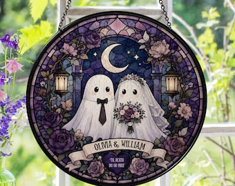 May include: A circular stained glass suncatcher featuring two ghosts, one wearing a black bowtie and the other a veil, holding a bouquet. The design includes a crescent moon, lanterns, and purple roses with a banner reading OLVIA & WILLIAM.