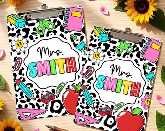 May include: Two rectangular clipboards featuring a black and white leopard print background. Each clipboard displays a central white scalloped label with the text Mrs. SMITH in colorful letters, surrounded by illustrations of school supplies.