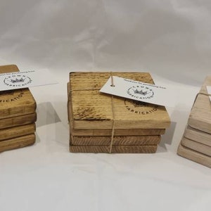 May include: Three stacks of square wooden coasters in varying shades of brown and tan. Each stack is tied with twine and has a small tag attached. The tags read "Thank you for purchasing from CROWN FABRICATION".
