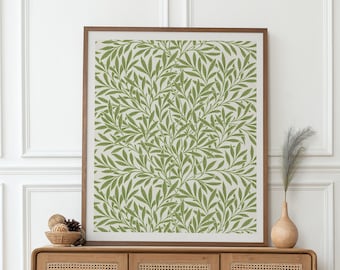 May include: A framed botanical print with a repeating pattern of green leaves on a cream background. The artwork is displayed above a wooden cabinet with woven door panels. A vase with decorative elements sits on the cabinet.