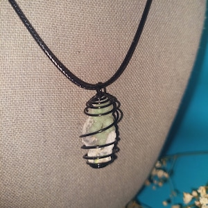 May include: A green crystal encased in a black wire spiral pendant on a black cord necklace.