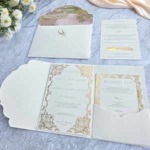 May include: Ivory wedding invitation suite with gold foil accents. The invitation features the names Holly Jade Meier and Thomas James Rogan, with the date 21.03.2026. Includes an envelope with a landscape design and a recovery day card.