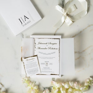 Invitation de mariage Lux en boîte blanche. Invitation en papier doré, encre noire, sceau de cire doré et carte de détail.