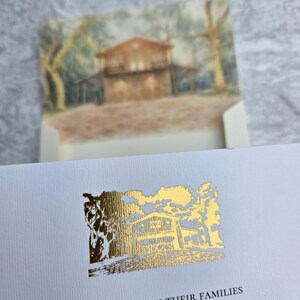 K&ouml;nnte beinhalten: Cremefarbene Einladung mit goldfarbenen Akzenten. Das Design zeigt eine detaillierte Illustration eines Hauses und B&auml;ume. Der Text "TOGETHER WITH THEIR FAMILIES" ist unter der Illustration gedruckt. Der Umschlag hat ein Aquarellgem&auml;lde des Hauses.