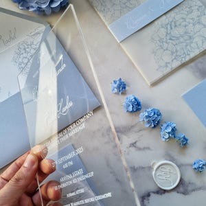 Gepersonaliseerde blauwe acryltrouwuitnodiging, met hydrangea ontwerp en aanpasbare locatiekaart en RSVP-kaart.