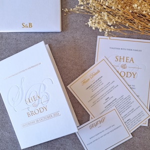 Invitation de mariage luxe rigide avec poche, RSVP et carte de détails, papier blanc, impression en or et embossage clair.