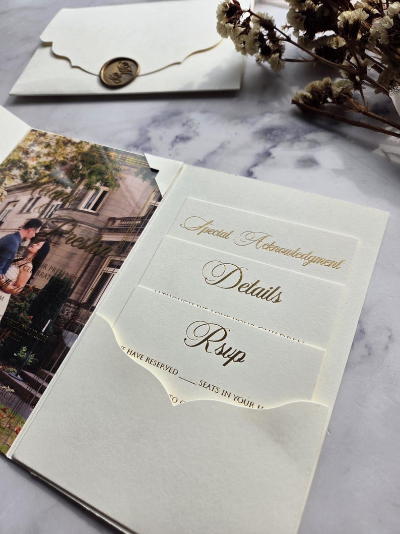 May include: A white wedding invitation with a gold foil design. The invitation has a pocket for a RSVP card. The text on the invitation reads "Special Acknowledgment", "Details", and "Rsvp".