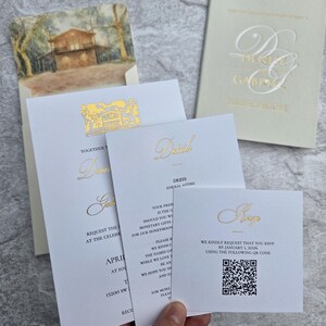 K&ouml;nnte beinhalten: Hochzeitseinladungs-Set mit goldfarbenem Folienschriftzug auf wei&szlig;em und cremefarbenem Karton. Enth&auml;lt Einladungs-, Detail- und RSVP-Karten. Die Einladung zeigt die Namen "Denis & Gabriel". Die RSVP-Karte enth&auml;lt einen QR-Code.