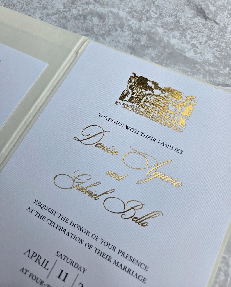 K&ouml;nnte beinhalten: Eine Hochzeitseinladung mit goldfarbenen Buchstaben und einer goldenen Illustration eines Geb&auml;udes. Die Einladung enth&auml;lt die Namen "Denise" und "Aguero" und "Gabriel Belle" sowie das Datum "11. April". Der Text lautet: "Bitten Sie um die Ehre Ihrer Anwesenheit bei der Feier ihrer Hochzeit."