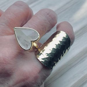 Puede incluir: Dos anillos de oro, uno con una piedra grande de coraz&oacute;n transparente y el otro una banda martillada.