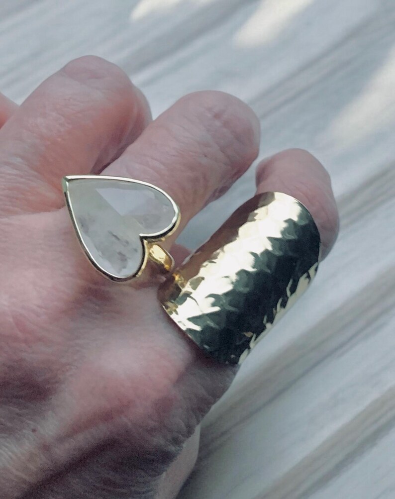 Puede incluir: Dos anillos de oro, uno con una piedra grande de coraz&oacute;n transparente y el otro una banda martillada.