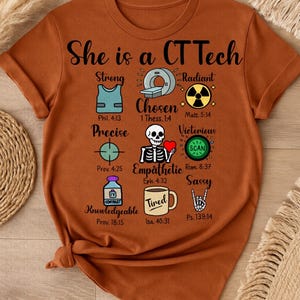 Puede incluir: Camiseta de color óxido con el texto "She is a CT Tech" y varios gráficos de temática médica. La camiseta presenta ilustraciones y palabras como "Strong", "Chosen" y "Radiant".