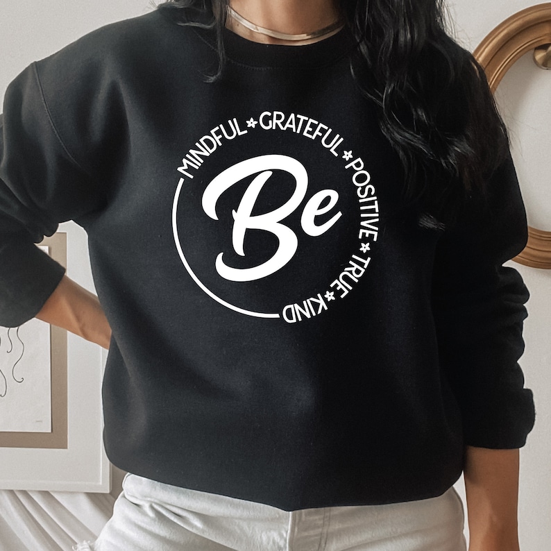 May include: Black sweatshirt with a white circle graphic that says "Be" with the words "Mindful", "Grateful", "Positive", "True", and "Kind" around the circle.