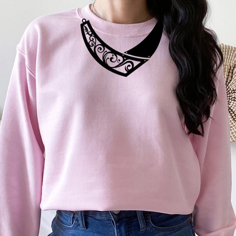 May include: A pink sweatshirt with a black, ornate, decorative necklace design.