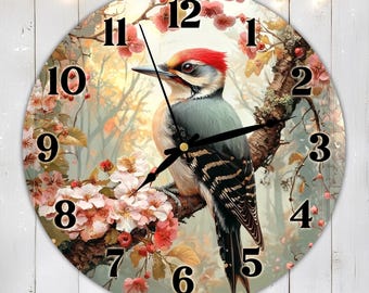 May include: A round clock with a woodgrain background featuring a colorful woodpecker perched on a branch with pink blossoms. The clock face has black Roman numerals and black hands.