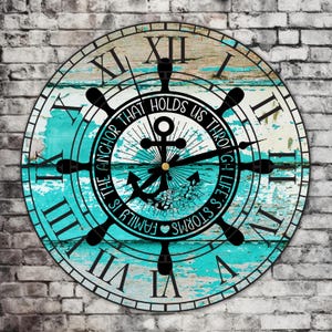 Könnte beinhalten: Eine runde Holzuhr mit einer blauen und weißen, abgenutzten Lackierung. Das Zifferblatt der Uhr zeigt einen schwarzen Anker mit dem Text "Der Anker, der uns durch die Stürme des Lebens hält, ist die Familie".