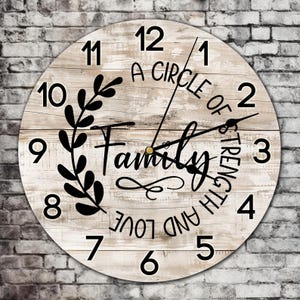 Op de afbeelding: Een witte houten klok met zwarte cijfers en wijzers. De wijzerplaat van de klok heeft een verweerde houten look en bevat de tekst "A Circle of Strength and Love Family".