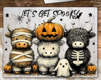 Puede incluir: Tabla de cortar rectangular con temática de Halloween. Presenta tres vacas de las Tierras Altas disfrazadas, un fantasma, calabazas y el texto "LET'S GET SPOOKY". Un cuchillo descansa encima.