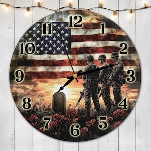 May include: Round wall clock featuring an American flag design with a sunset backdrop and silhouettes of soldiers. The clock face displays black numerals and hands, with a floral border at the bottom. The clock measures approximately 12 inches in diameter.