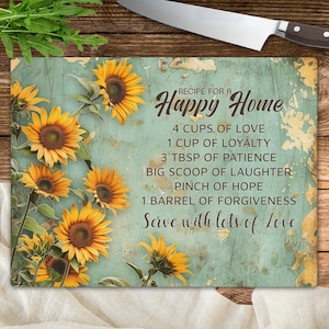 May include: A blue and white distressed wooden cutting board with a sunflower design and the text "RECIPE FOR A Happy Home 4 CUPS OF LOVE 1 CUP OF LOYALTY 3 TBSP OF PATIENCE BIG SCOOP OF LAUGHTER PINCH OF HOPE 1 BARREL OF FORGIVENESS Serve with lots of Love"
