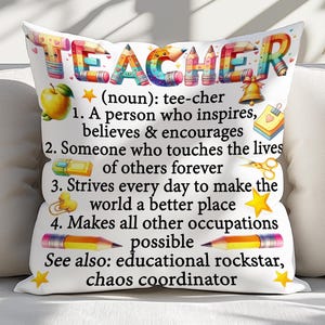 May include: White decorative pillow with the word "TEACHER" in colorful letters. The pillow includes a definition of a teacher, along with illustrations of an apple, bell, scissors, and pencils. The text also includes the phrases "educational rockstar" and "chaos coordinator."
