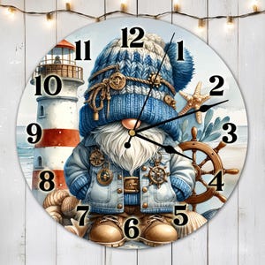 May include: A round clock featuring a blue and white gnome wearing a sailor hat and holding a ship's wheel. The clock face has Roman numerals and a white background. The gnome is standing on a beach with a lighthouse in the background.