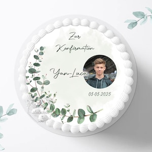 Könnte beinhalten: Weißer Kuchen, verziert mit einem grünen Eukalyptuskranz, einem Foto eines jungen Mannes und dem Text "Zur Konfirmation Yan-Luca 05-05-2025".