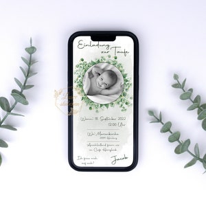 Op de afbeelding: Een digitale uitnodiging voor de doop van een baby met een foto van de baby in een krans van groene bladeren. De uitnodiging bevat de datum, tijd en locatie van het evenement. De tekst luidt: "Einladung zur Taufe Wann: 18 September 2022 12:00 Uhr Wo: Marienkirche 2009 Anschließend feiern wir im Cafe Heroglick Ich freue mich auf euch! Jacob"