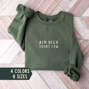 May include: A green sweatshirt with the text "AIM HIGH SQUAT LOW" in white lettering.
