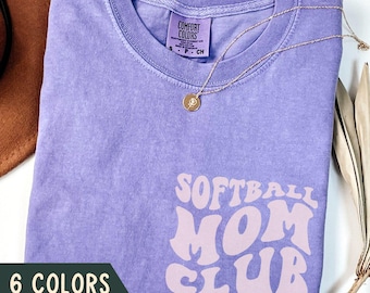 May include: Purple t-shirt with the text "Softball Mom Club" in a retro font. The text is in a light pink color. The shirt is available in 6 colors and 6 sizes.