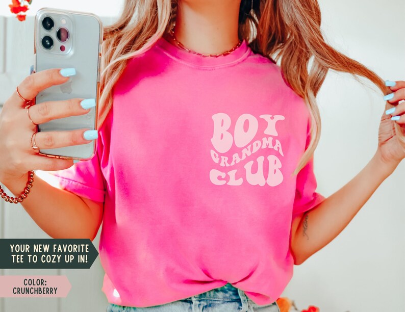 May include: Pink t-shirt with a white retro-style graphic that says "Boy Grandma Club".