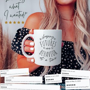 May include: White ceramic mug with the text "shaping FUTURES BEHAVIOR one at a time" in black script. The mug is held by a person. The image also includes customer reviews and the text "Exactly what I wanted!"