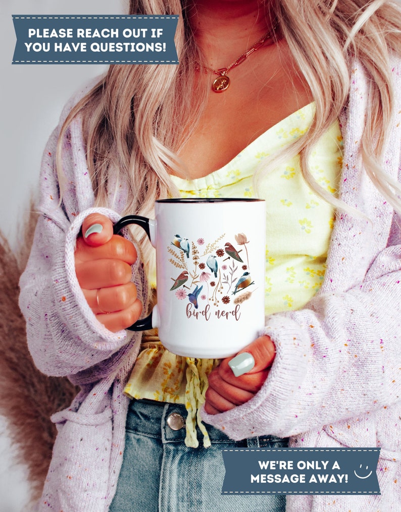 May include: White ceramic mug with a black handle and rim. The mug features a colorful illustration of birds and flowers with the text "bird nerd".