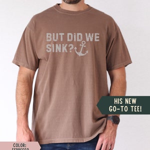 May include: A brown t-shirt with the text "BUT DID WE SINK?" and an anchor graphic. The text is in a distressed font.