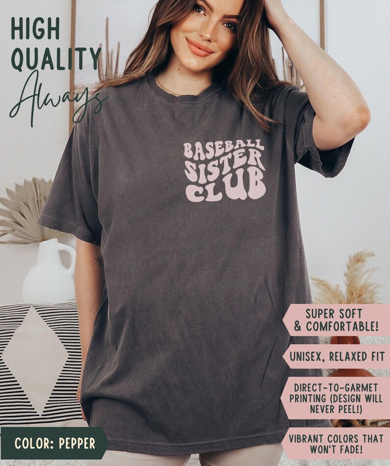 May include: Pepper-colored t-shirt with the text "BASEBALL SISTER CLUB" in a retro font. The shirt also has the text "HIGH QUALITY Always" and additional text that reads "SUPER SOFT & COMFORTABLE!" and "UNISEX, RELAXED FIT".