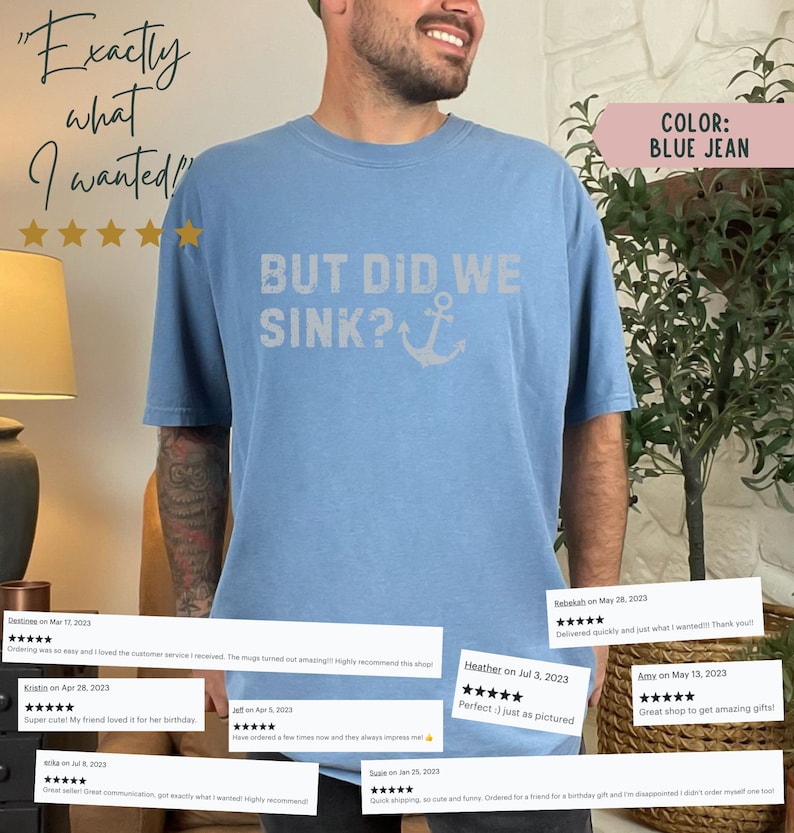 May include: A light blue t-shirt featuring the text "BUT DID WE SINK?" and an anchor graphic. The shirt is made from a soft, comfortable material and has a relaxed fit. The text is in a distressed white font. The anchor is white. The shirt is modelled on a person. The background is a blurred image of a plant and a lamp.