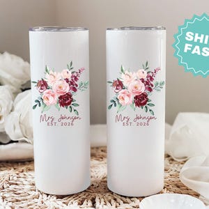 Puede incluir: Dos vasos aislados blancos con dise&ntilde;os florales. Cada vaso presenta un ramo de flores rosas y burdeos con hojas verdes. El texto "Mrs. Johnson EST. 2026" est&aacute; impreso debajo.