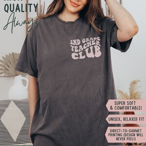 May include: Pepper-colored t-shirt with the text "2ND GRADE TEACHER CLUB" in a retro font. The shirt has a relaxed fit and is made of a soft, comfortable material. The design is printed with vibrant colors that won't fade.