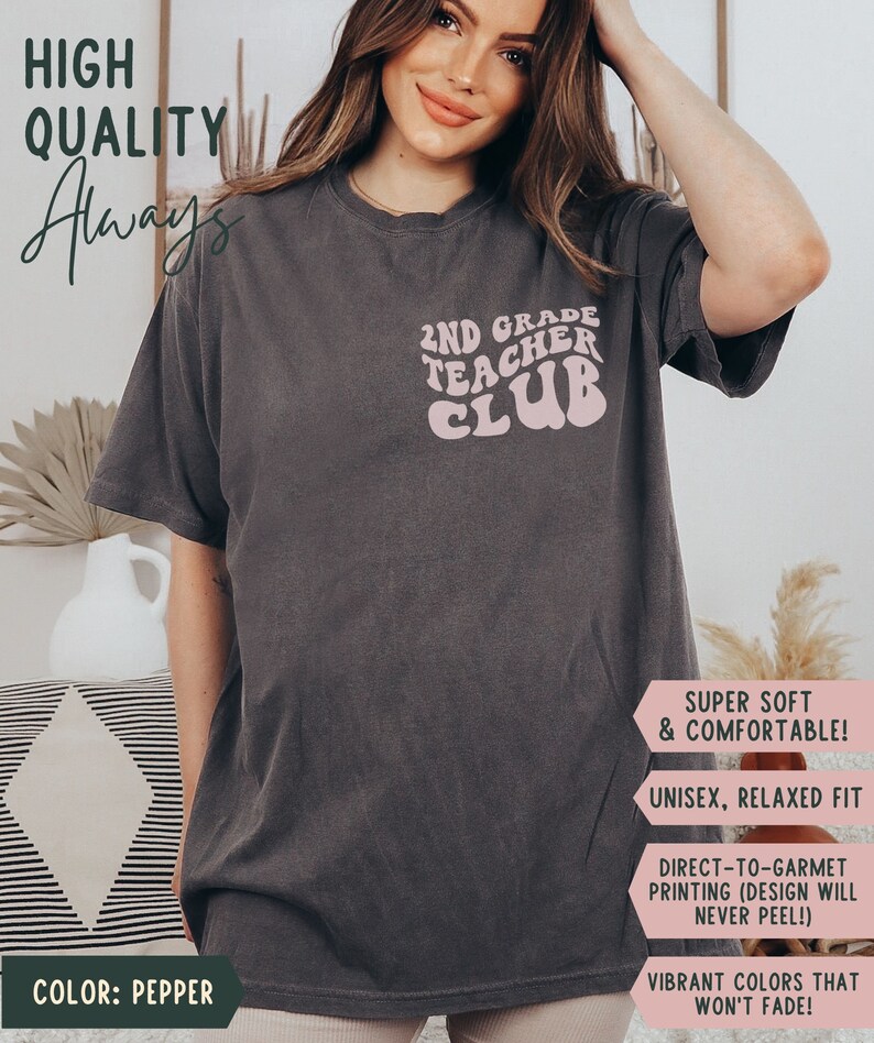 May include: Pepper-colored t-shirt with the text "2ND GRADE TEACHER CLUB" in a retro font. The shirt has a relaxed fit and is made of a soft, comfortable material. The design is printed with vibrant colors that won't fade.