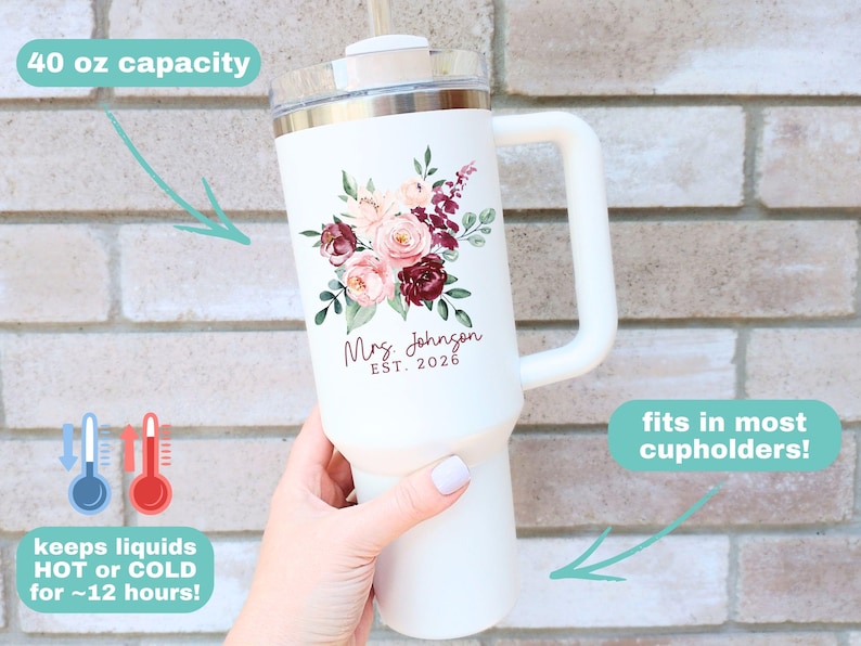 Puede incluir: Vaso t&eacute;rmico blanco con asa, decorado con un dise&ntilde;o floral en tonos rosas y burdeos. El vaso tiene una capacidad de 1,18 litros y el texto "Mrs. Johnson EST. 2026". Mantiene los l&iacute;quidos calientes o fr&iacute;os durante unas 12 horas.