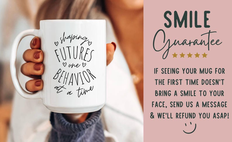 May include: White ceramic mug with the text "shaping FUTURES one BEHAVIOR at a time" in black script. The mug is held by a person. A pink background with the words "SMILE Guarantee" and a refund policy is visible.