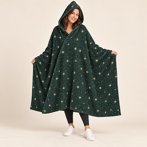 May include: A dark green hooded wearable blanket featuring a repeating pattern of gold starbursts and small white dots. The fleece-like garment drapes over the shoulders and body, providing full coverage with an attached hood and open front design.
