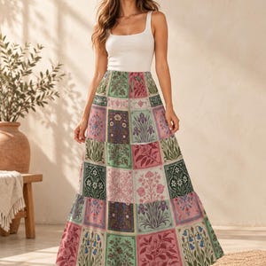 May include: A floor-length maxi skirt featuring a multi-colored patchwork design with various floral and botanical illustrations in shades of green, pink, and cream. The skirt has a high-waisted fit and a tiered silhouette that flows to the ankles.