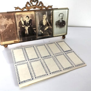 May include: Vintage brass-coloured photo frame with four portrait slots, each holding a black and white photograph. The frame has a decorative bow at the top and rests on small, round feet. A sheet of blank photo cards with blue borders is in front.