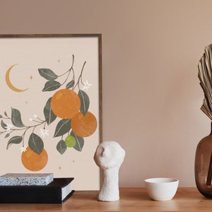 May include: A framed print of a stylized illustration of an orange tree with white blossoms and fruit. The background is a light peach color with a crescent moon and stars.