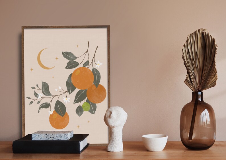 May include: A framed print of a stylized illustration of an orange tree with white blossoms and fruit. The background is a light peach color with a crescent moon and stars.