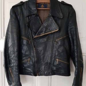 May include: A dark green leather motorcycle jacket with a zipper closure and multiple pockets. The jacket has a label with the text "ATF" inside a triangle.