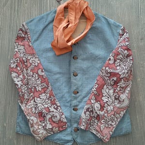 May include: A blue linen jacket with a mandarin collar and floral patterned sleeves. The jacket has five buttons down the front and a matching orange scarf.